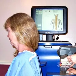 Patient during a spinal scan with a computer screen showing the spine