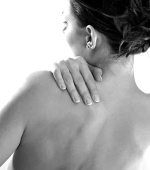 Black and white photo of a woman holding her sore shoulder